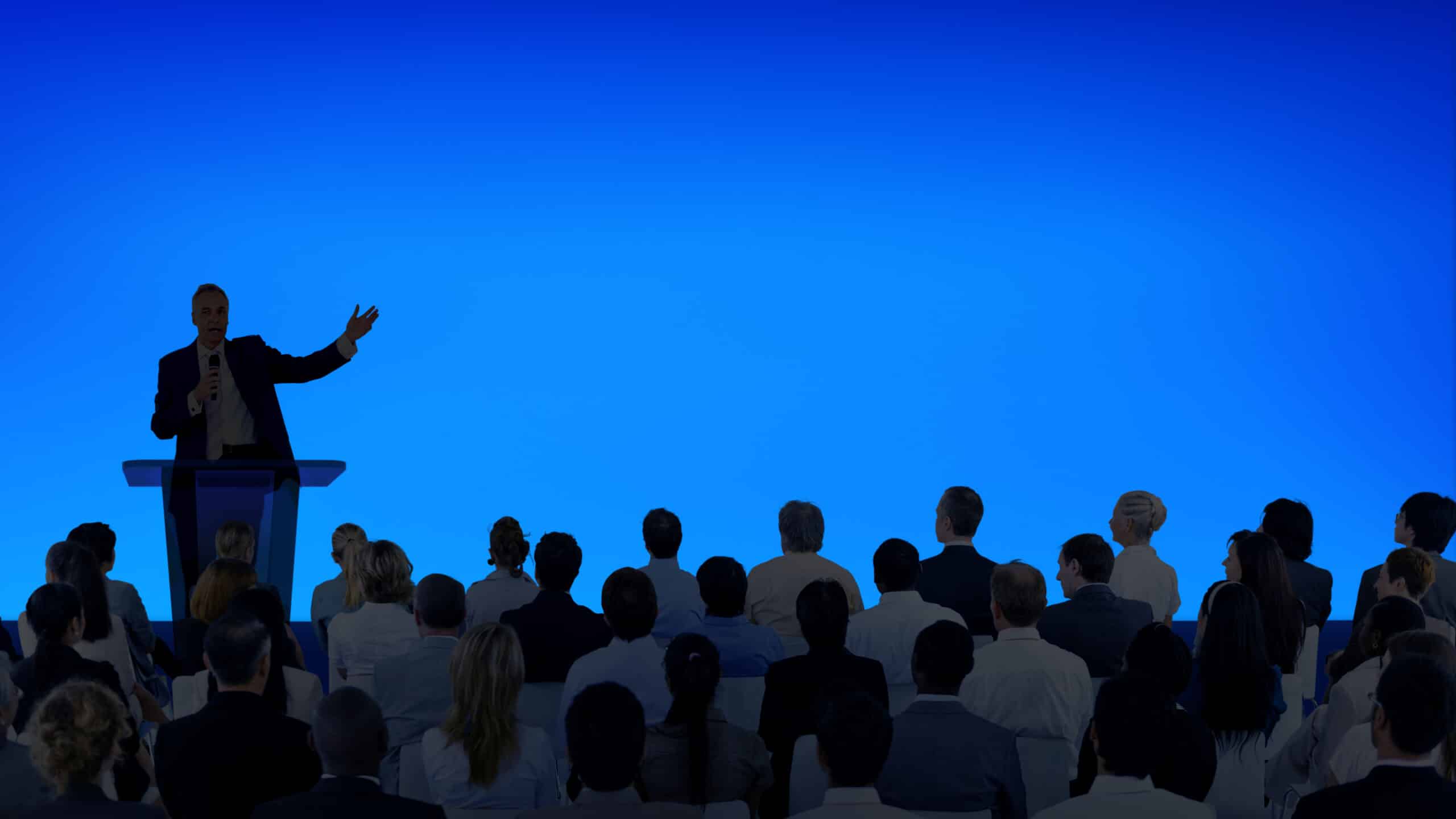 Corporate businessman giving a presentation to a large audience